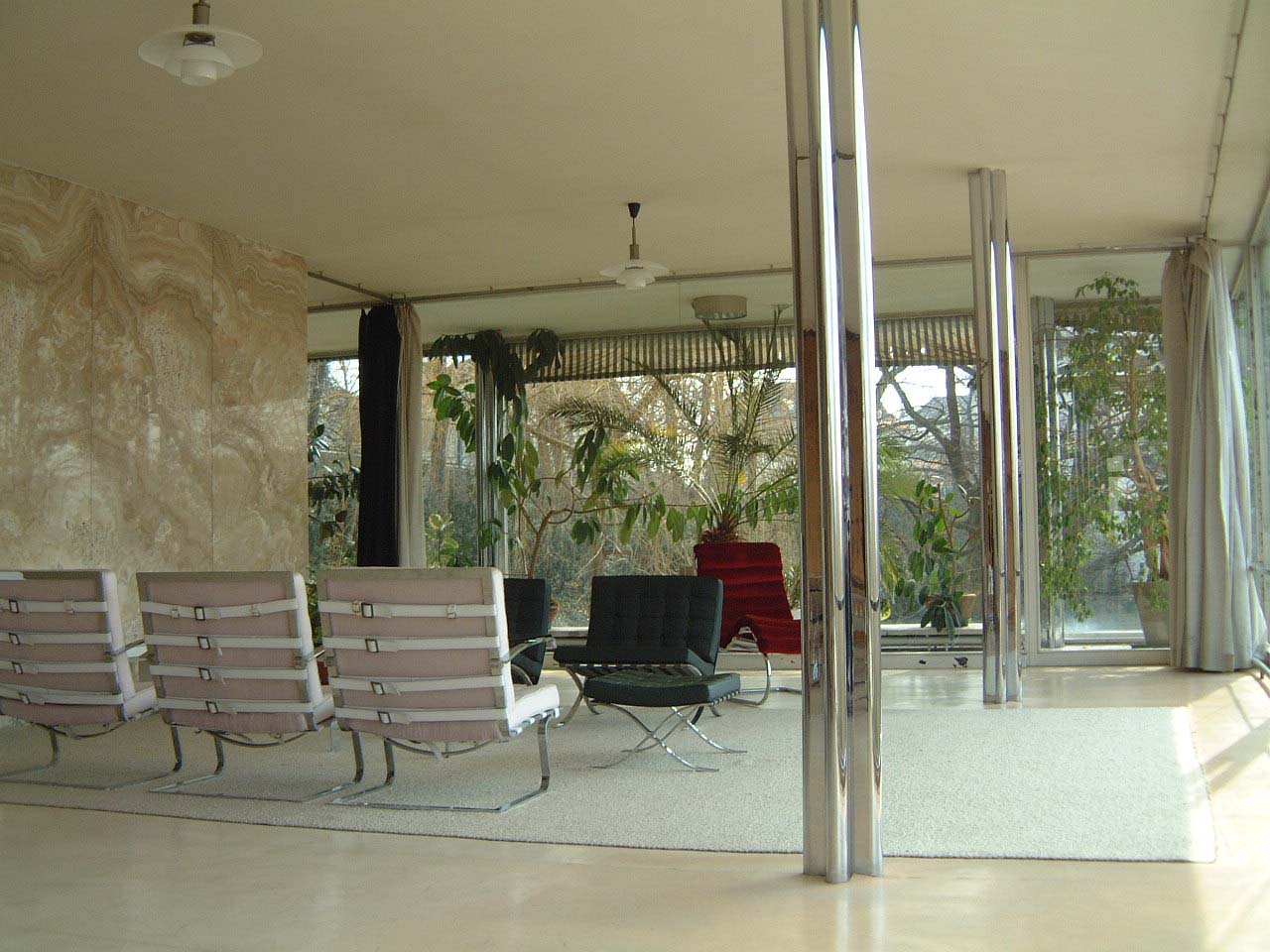 Sala de estar da Villa Tugendhat em Brno, com a parede de ônix âmbar e colunas cromadas